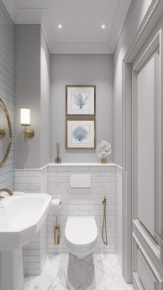 a white toilet sitting next to a sink in a bathroom under a framed art piece