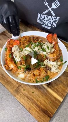 a person in black gloves is holding a plate of food with shrimp and carrots on it