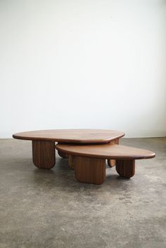 two wooden tables sitting on top of each other in front of a white wall and concrete floor