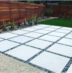 a concrete patio with grass and wooden fence in the background