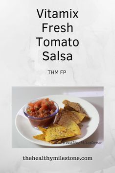 a white plate topped with tortilla chips and salsa next to a bowl of salsa