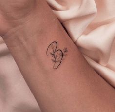 a woman's arm with a small heart tattoo on the left side of her arm