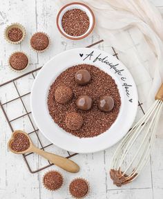 a white bowl filled with chocolate truffles next to some whisks on a wire rack