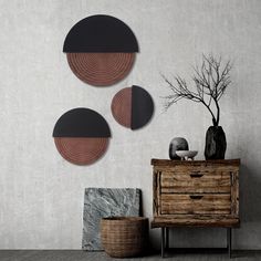 three circular metal wall art pieces hanging on the wall next to a dresser and vase