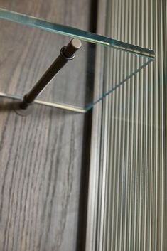 a glass shelf sitting on top of a wooden floor next to a metal handle and door