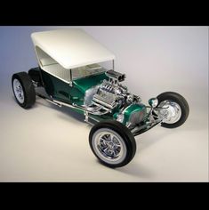 a green and white model t car on a gray background with the hood up to show it's engine