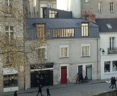 several people walking down the street in front of some buildings with windows and balconies