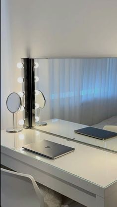 a white desk topped with a laptop computer next to a wall mounted mirror and lights