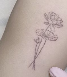 a woman's thigh with a single flower tattoo on her left side ribcage