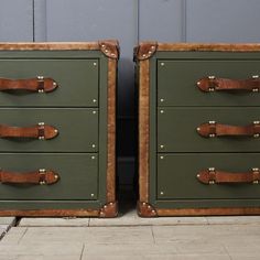 two green chests with leather handles are sitting side by side in front of a blue wall