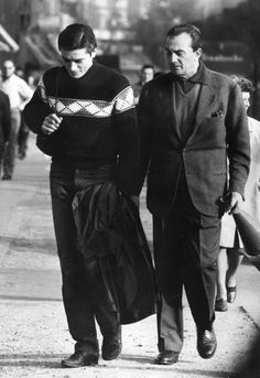 an old photo of two people walking down the street