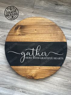 a round wooden sign that says gather here with grateful hearts on the front and bottom