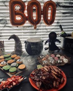 a table topped with lots of halloween treats and balloons in the shape of boos