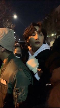 two young men standing next to each other in front of a building at night time