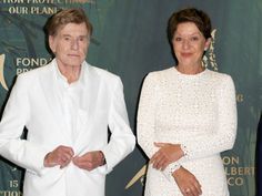 two people standing next to each other on a red carpet