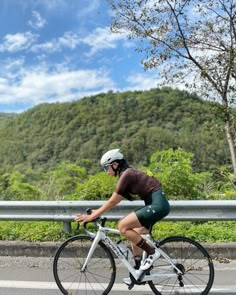 a person riding a bike on a road with mountains in the background