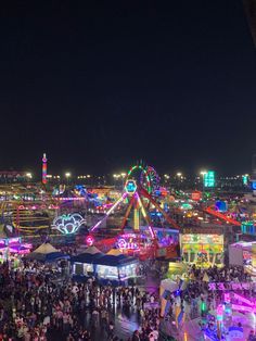 an aerial view of the fairground at night with many rides and people walking around