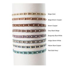 a stack of different colored bracelets on top of a white vase with the names of each