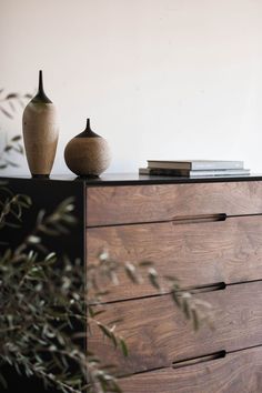 two vases sitting on top of a wooden dresser