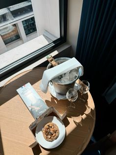 a table that has some food on it and wine glasses in front of the window