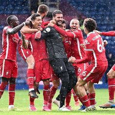 a group of soccer players celebrating on the field in the rain with their arms around each other