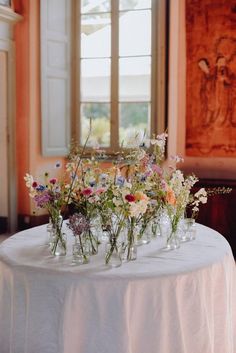 flowers are arranged in vases on a table with a white linen draped over it