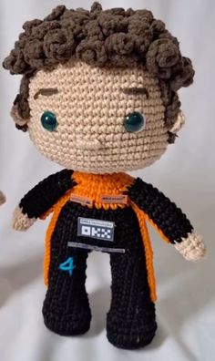 a small crocheted doll is posed on a white background with an orange and black outfit