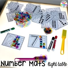 a table topped with lots of crafting supplies and numbers for kids to color on