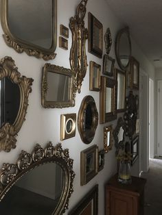 there are many mirrors on the wall and one is hanging up against the white wall