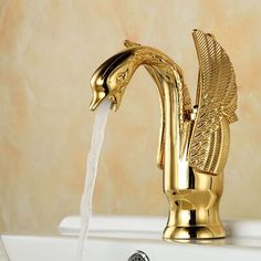 a golden faucet with water running from it's sides and an egyptian bird design on the side