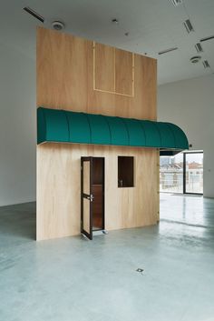 an empty room with a green awning and two open doors on the side of it