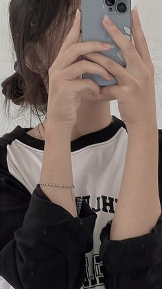 a woman taking a selfie with her cell phone in front of her face while wearing a black and white shirt