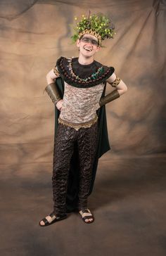 a man with a crown on his head standing in front of a photo studio backdrop