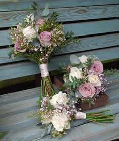 two bridal bouquets sitting on top of a wooden bench next to each other