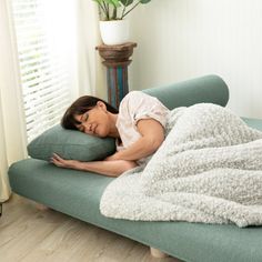 a woman is sleeping on a couch with a blanket