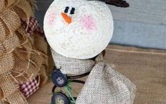 a snowman made out of burlock and buttons sitting next to a burlock