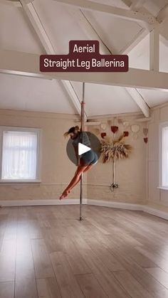 a woman is dancing on a pole in the middle of an empty room with windows