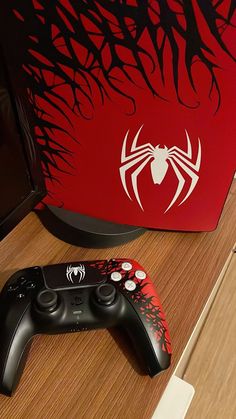 two video game controllers sitting on top of a wooden table next to a red box