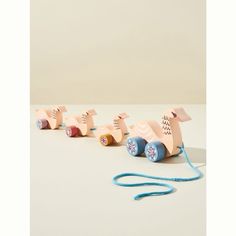 four wooden toys are lined up in a row on a table with a blue cord