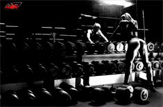 two women are in the gym with dumbbells and one is squatting down