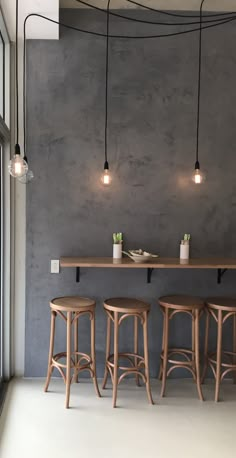 three stools in front of a bar with lights hanging from it's ceiling