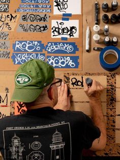 a man writing on a wall covered in graffiti