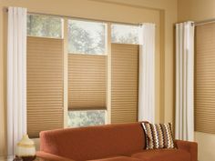 a living room filled with furniture and windows covered in blind shades on top of them