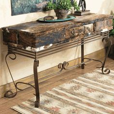 a table with a bowl on top of it next to a rug and potted plants