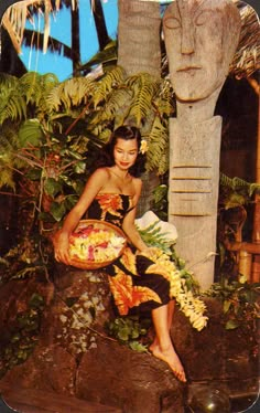 a woman sitting on top of a rock next to a plant filled with leaves and flowers