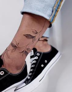 a woman's foot with a flower tattoo on her left ankle and the bottom part of her leg