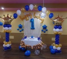 a table with balloons and decorations for a first birthday party in blue, gold and white