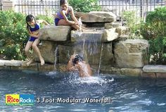 two people sitting on the edge of a swimming pool, one person jumping into the water