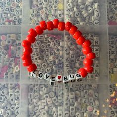 a red beaded bracelet with the word love bug spelled in small letters on it