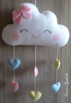 a cloud shaped mobile with hearts hanging from it's sides on a wooden surface